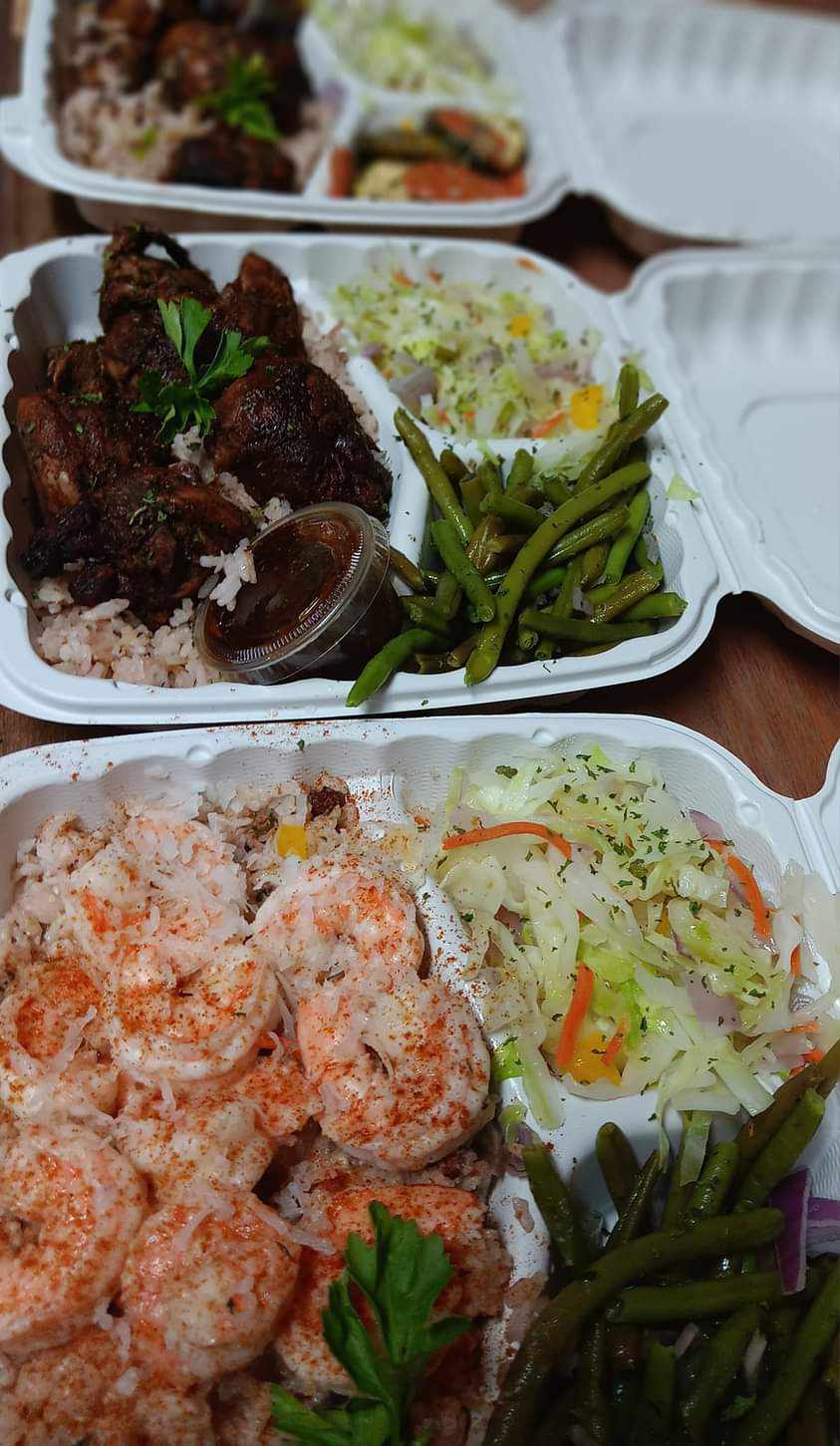 Three white styrofoam take-out containers filled with a meal, including shrimp, chicken and rice, cole slaw, and green beans, prepared by Sun Connect Foods & Services LLC, Keansburg, New Jersey and arranged on a wooden table.